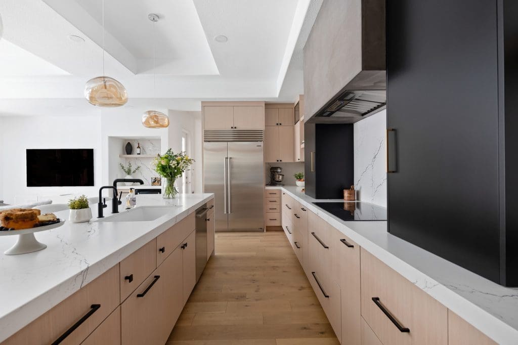 Modern kitchen with warm wood cabinetry, quartz counters, and inviting pendant lighting for gatherings.