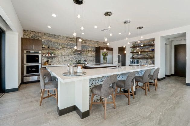 Modern kitchen with white island, wood cabinetry, and natural stone wall by Reveal Interior Design.