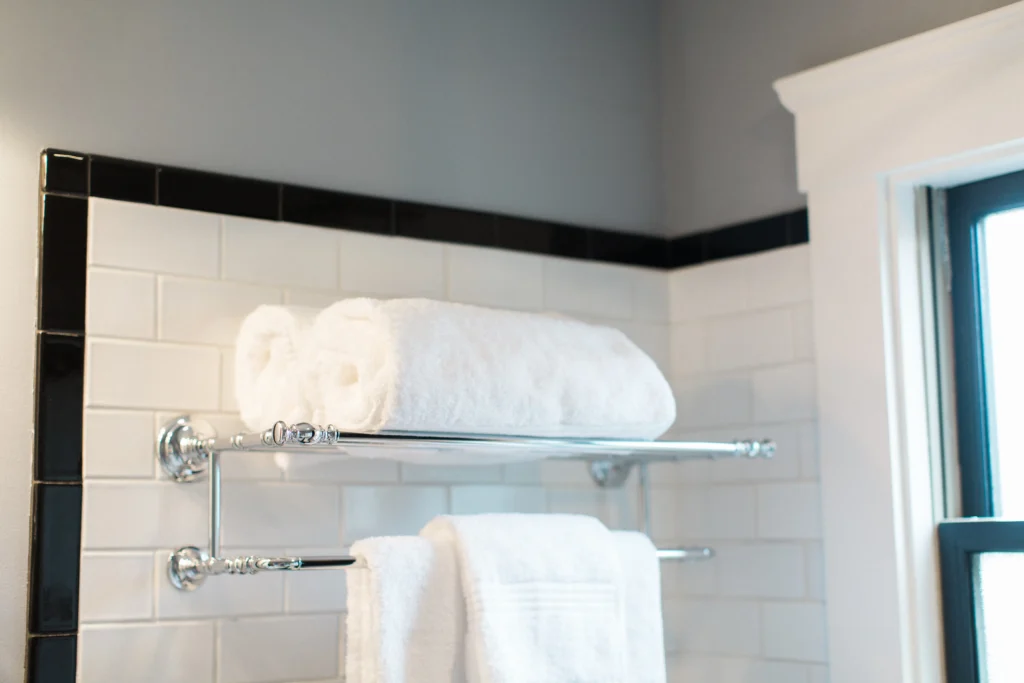 Elegant towel rack on classic tiles, illuminated by natural light in a serene bathroom design.