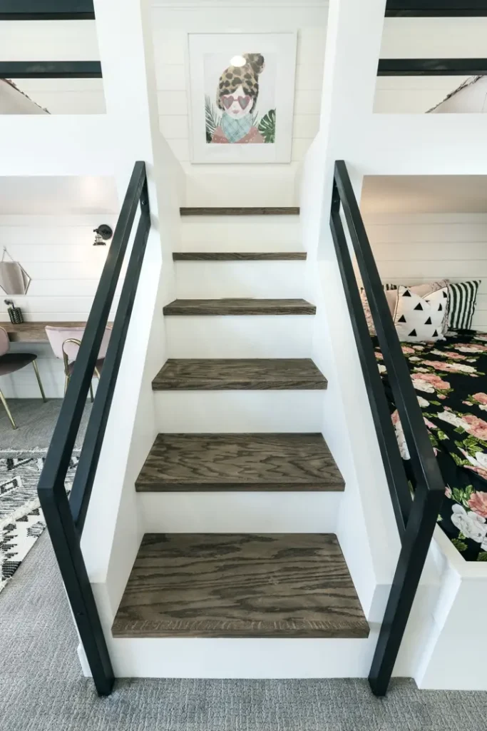 Sleek modern staircase with dark wood steps, black railings, and vibrant artwork above.