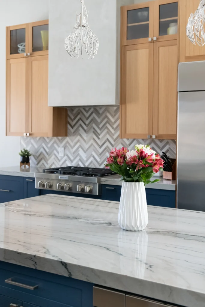 Modern kitchen featuring marble countertop, blue cabinetry, and elegant floral accents.