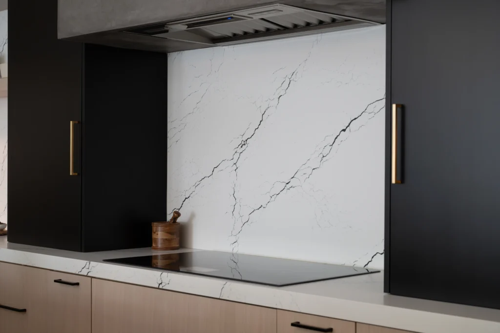 Sleek modern kitchen with white marble backsplash, warm wood cabinets, and chic black accents.