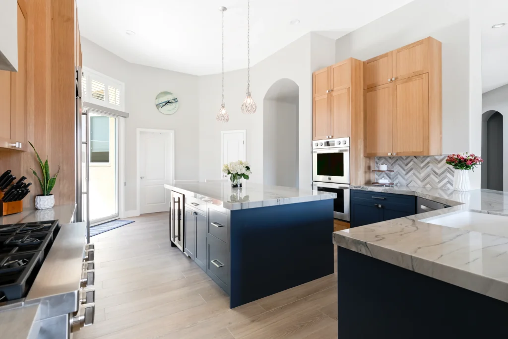 Modern kitchen with navy blue island, light wood cabinetry, and bright airy ambiance.