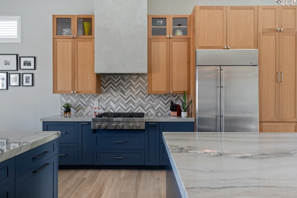 Modern kitchen with chic island, navy cabinetry, marbled countertop, and elegant herringbone backsplash.