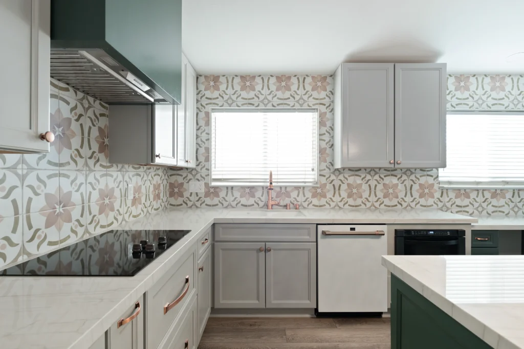 Stylish kitchen with green-gray cabinets, floral backsplash, and modern appliances, ideal for entertaining.