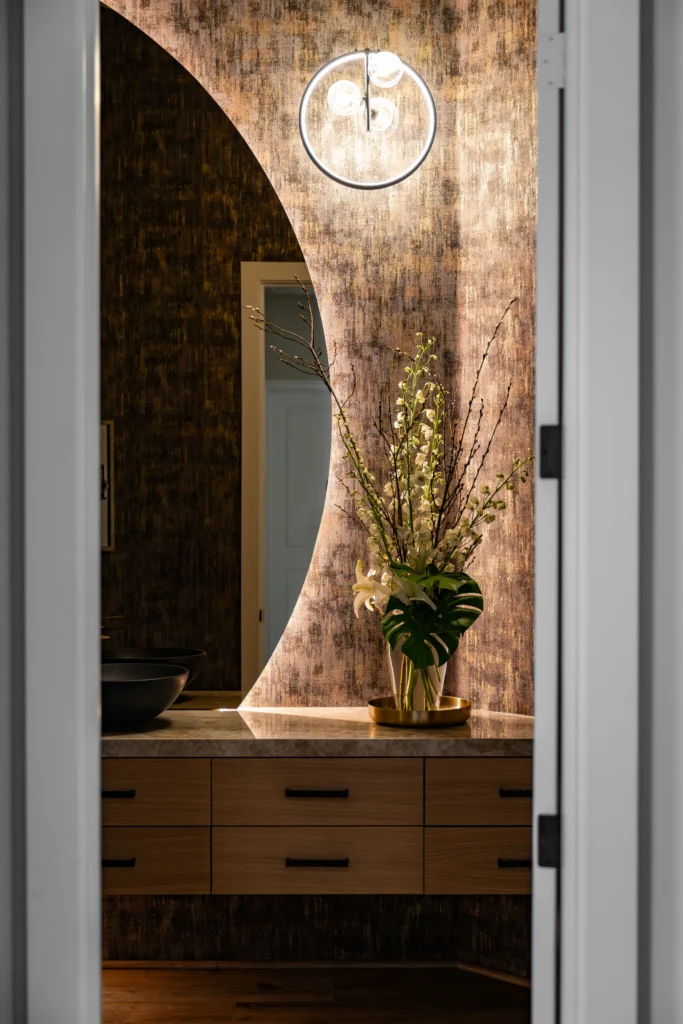 Stylish bathroom vanity with warm tones, contemporary lighting, and greenery for a chic Alpine feel.