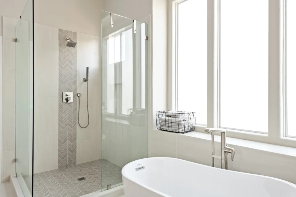 Modern bathroom oasis with a stunning walk-in shower and elegant freestanding tub by Reveal Interior Design.