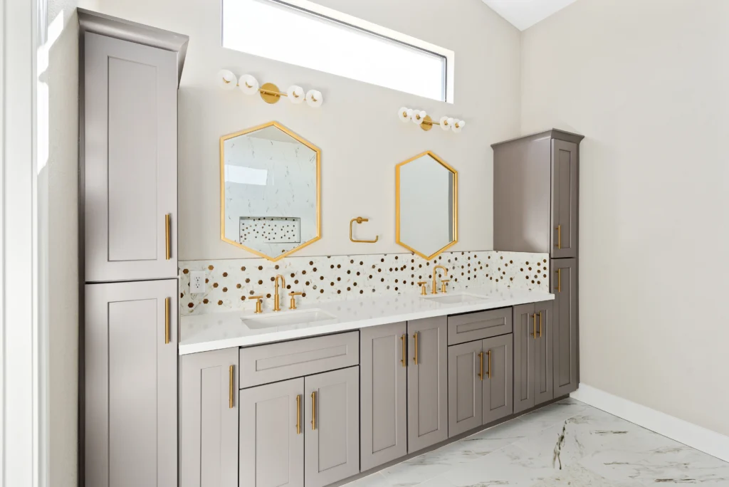 Sleek gray bathroom featuring hexagonal mirrors, gold accents, and luxurious marble flooring.