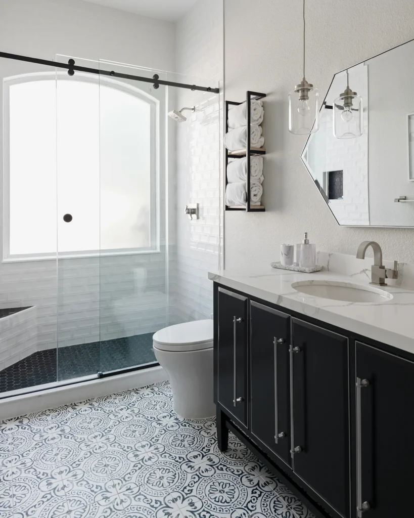 Contemporary black and white bathroom with minimalist design, glass shower, and geometric flooring.