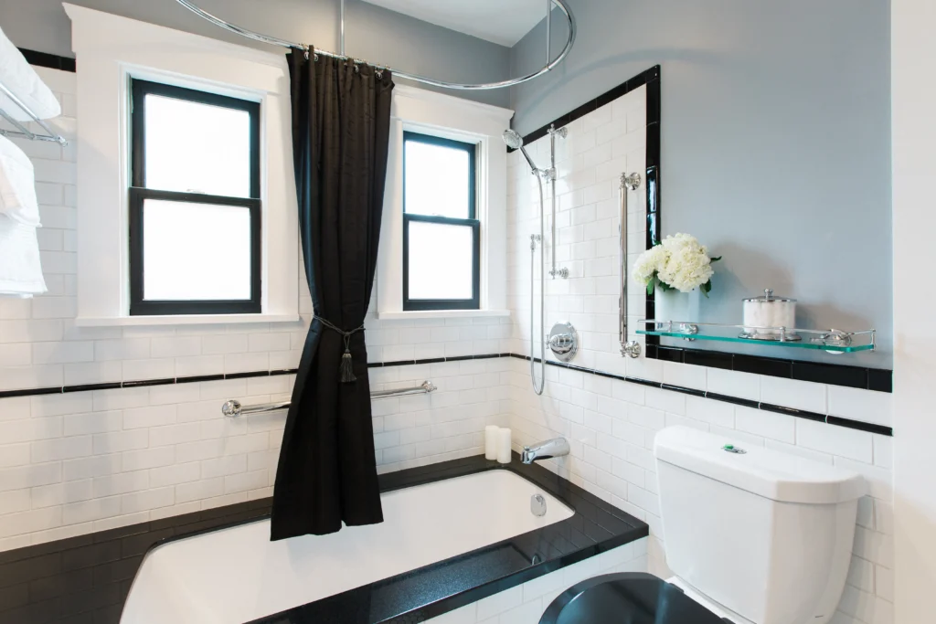 Sleek modern bathroom with white bathtub, black-and-white tiles, and natural light accents.