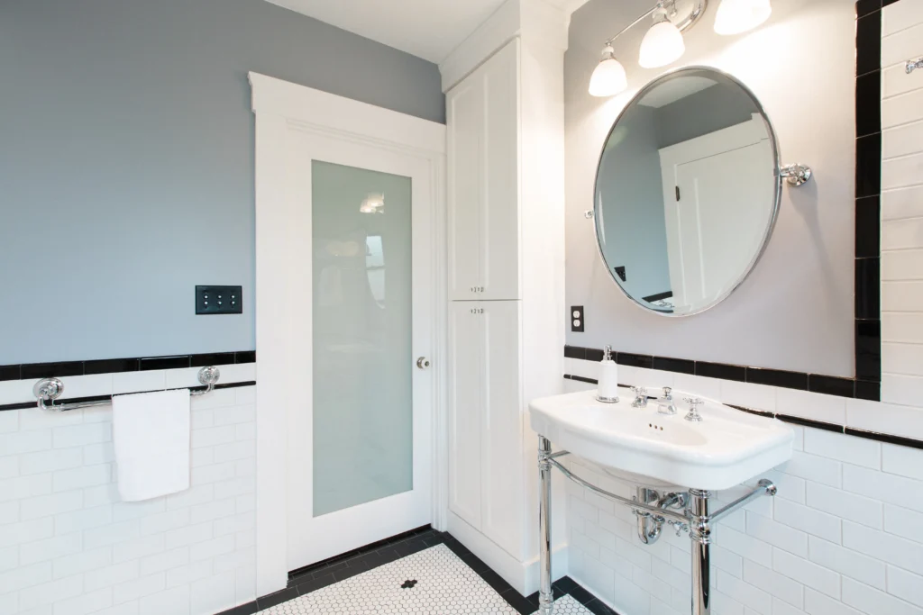 Contemporary Valley project bathroom with gray walls, sleek sink, round mirror, and classic tiled floor.