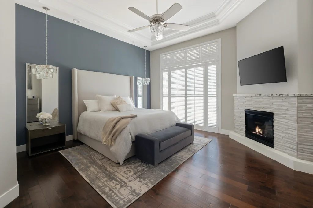 Chic bedroom featuring plush bedding, blue walls, sleek decor, and a cozy fireplace.