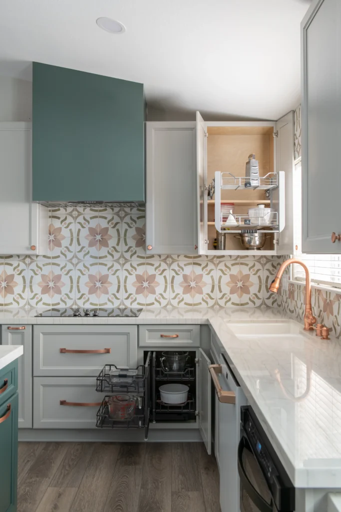 Elegant modern kitchen with muted green cabinetry, geometric backsplash, and polished stone countertop.