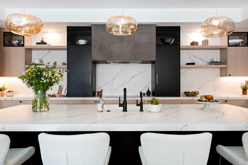 Modern kitchen featuring a white marble island, gold pendant lights, and stylish cabinetry design.