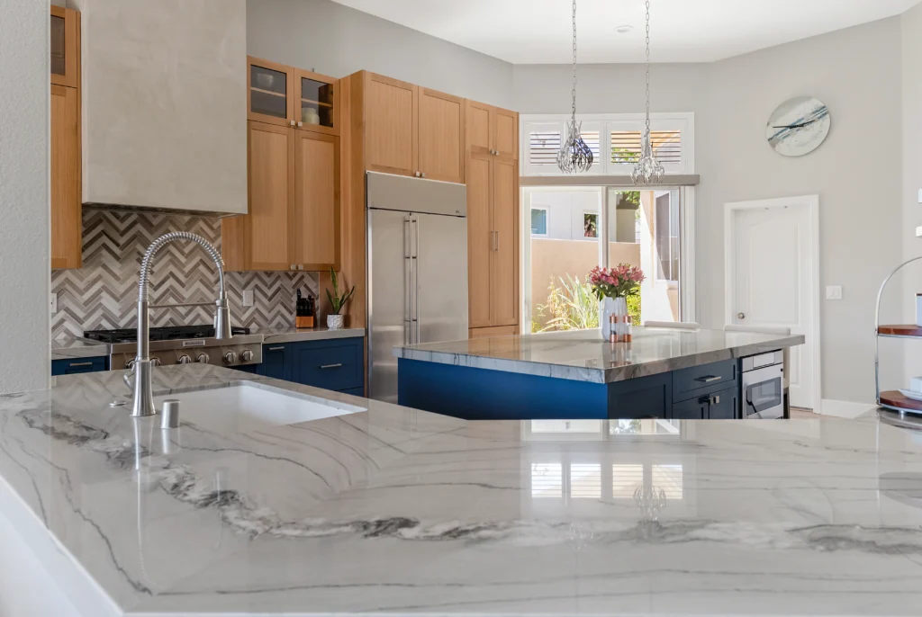 Inviting modern kitchen with light wood, blue island, and natural light for entertaining.