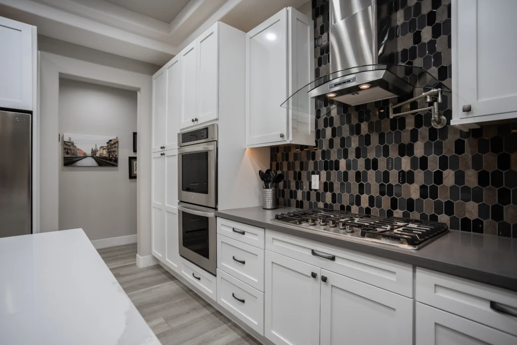 Bright modern kitchen featuring white cabinets, gray island, and stylish hexagonal backsplash.