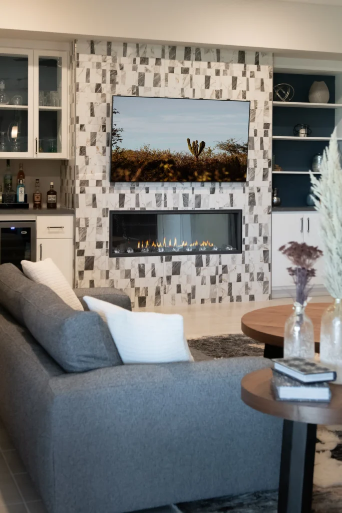 Contemporary living room with geometric tile wall, gray sofa, and stylish mini-bar for relaxation.