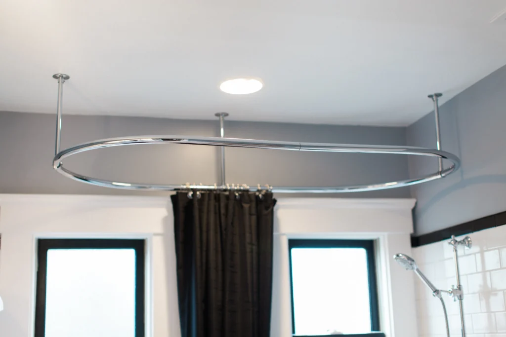 Sleek oval shower rod and dark curtain enhance the modern elegance of The Valley bathroom design.