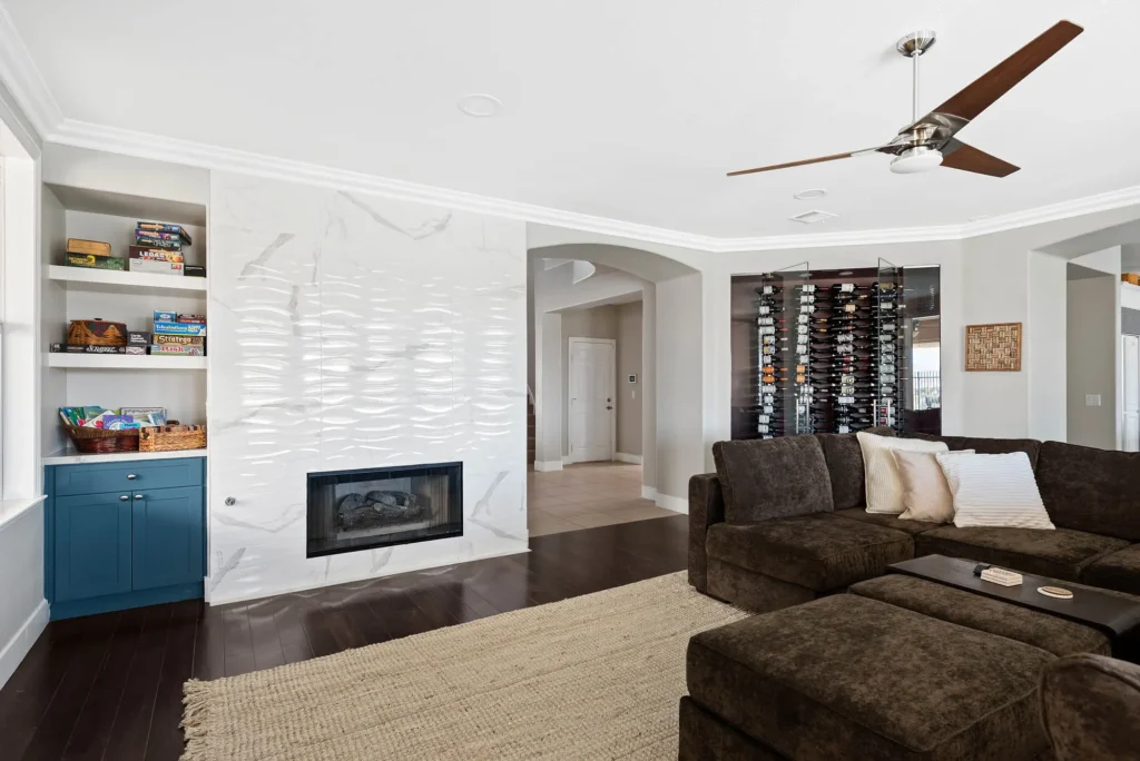 Inviting modern living room with brown sectional sofa, fireplace, blue shelves, and dark wood flooring.