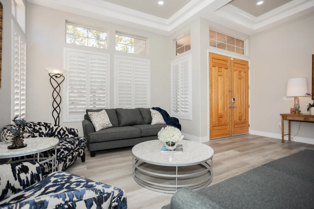 Elegant living room with grey sectional, navy accents, and natural light for a cozy atmosphere.