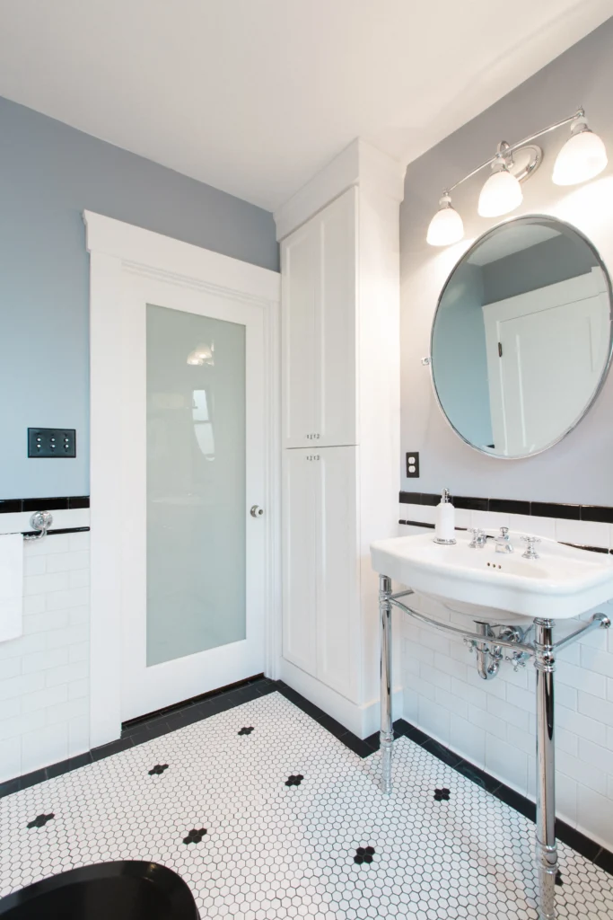 Stylish modern bathroom with gray walls, round mirror, and black-and-white checkered flooring.