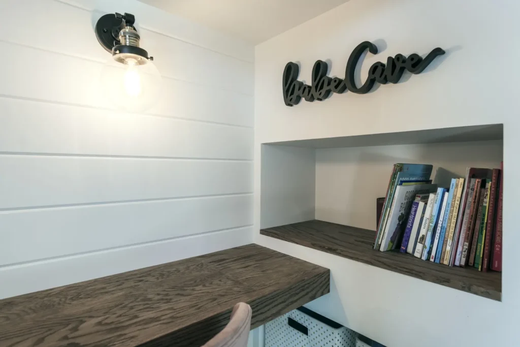 Cozy Workspace Haven: The Harvard Interior Design Project Cozy workspace with white wooden walls, dark desk, pink chair, and industrial light fixture.