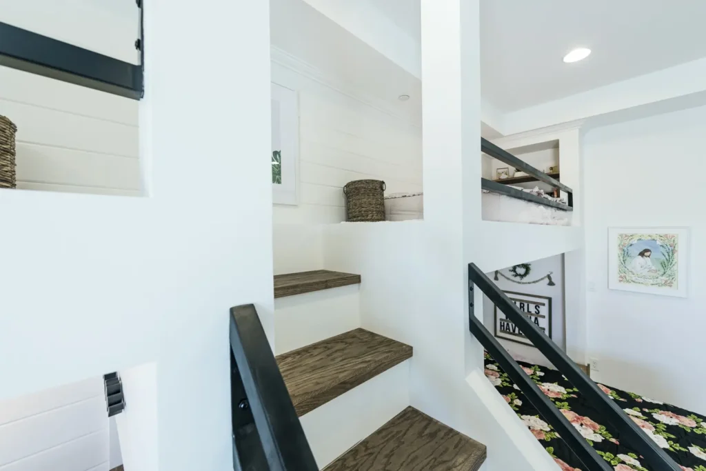 Modern Staircase Design in The Harvard Project Modern staircase with wooden treads, black railings, and a cozy nook featuring a floral blanket.