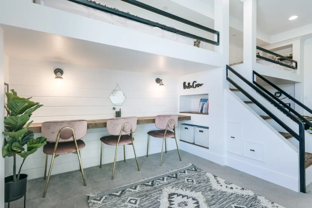 Modern minimalist workspace featuring a wooden table, blush stools, and bright white interiors.