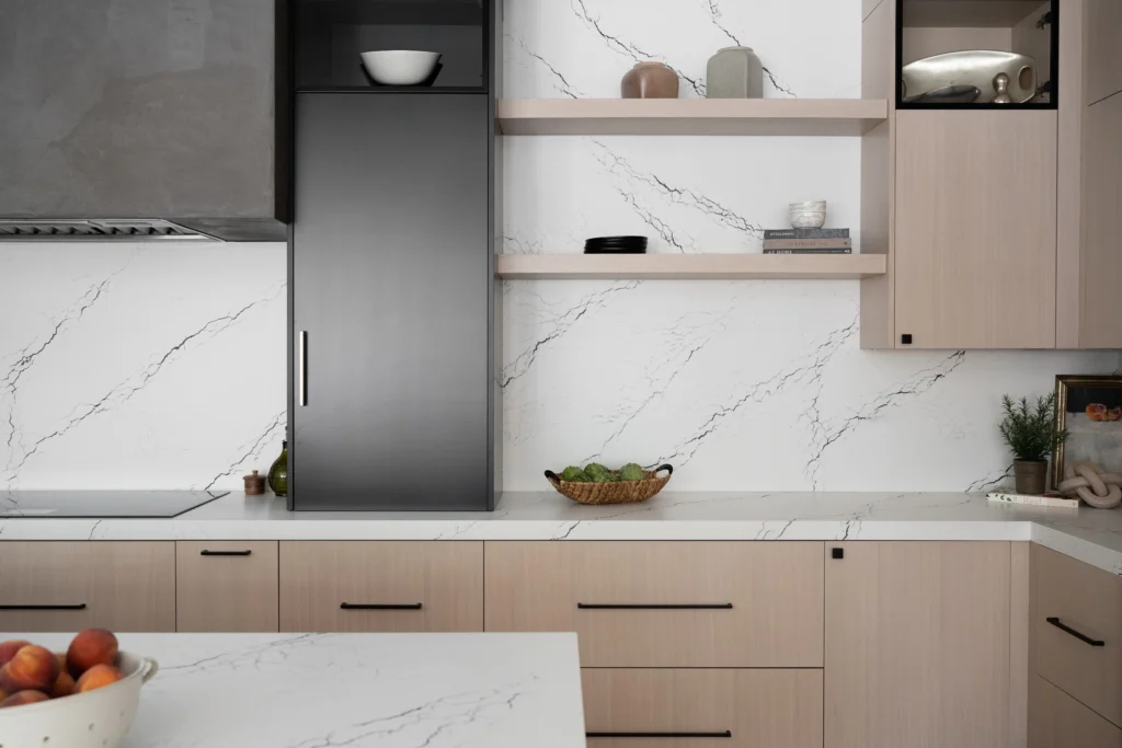 Sleek modern kitchen with minimalist design, light wood cabinetry, and elegant marble countertops.