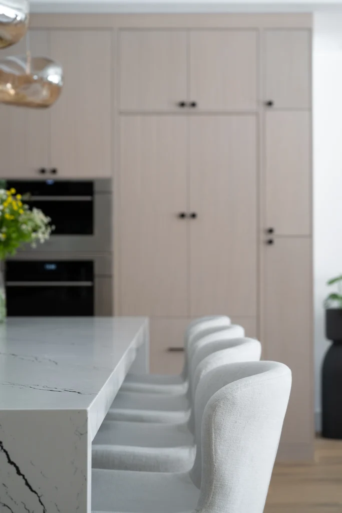 Sleek modern kitchen with elegant island, muted cabinetry, and warm touches of nature.