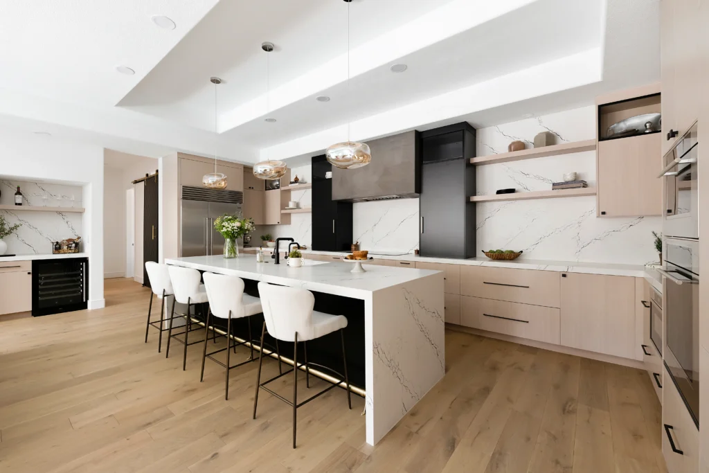 Sleek modern kitchen with white island, bar stools, and pale wood cabinetry in The Lilo Project.