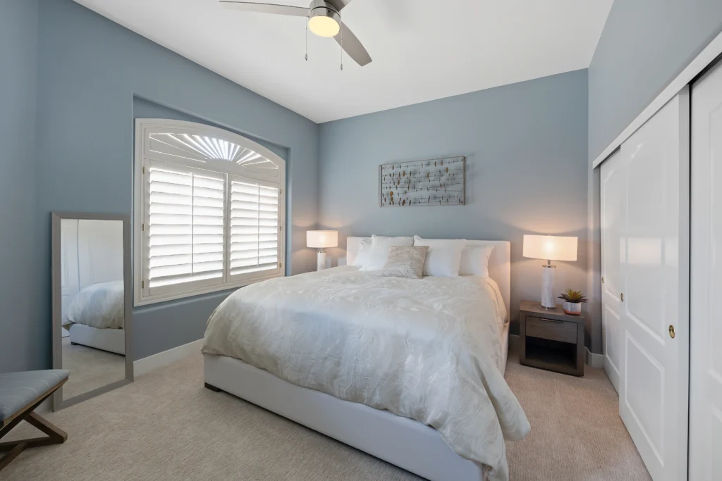 Elegant blue guest bedroom with natural light, plush bedding, and a serene, inviting ambiance.