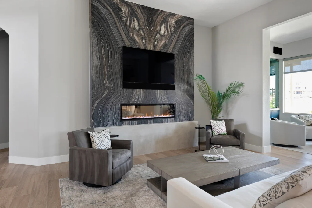 Modern living room with dark stone wall, sleek fireplace, and plush seating by Reveal Interior Design.