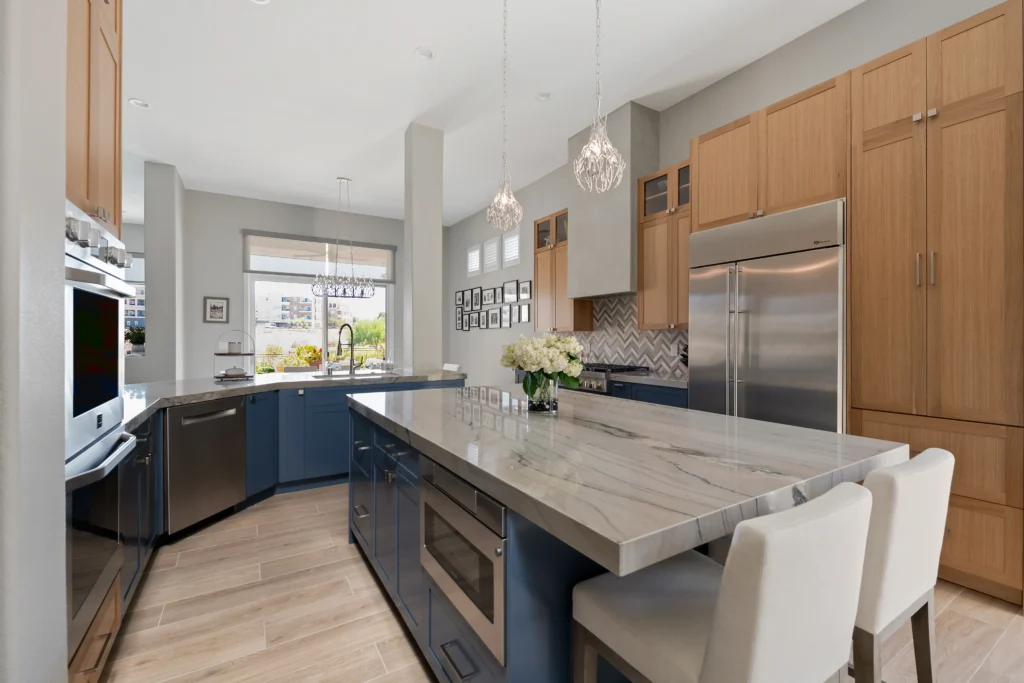 Elegant modern kitchen with marble island, blue cabinetry, and abundant natural light.