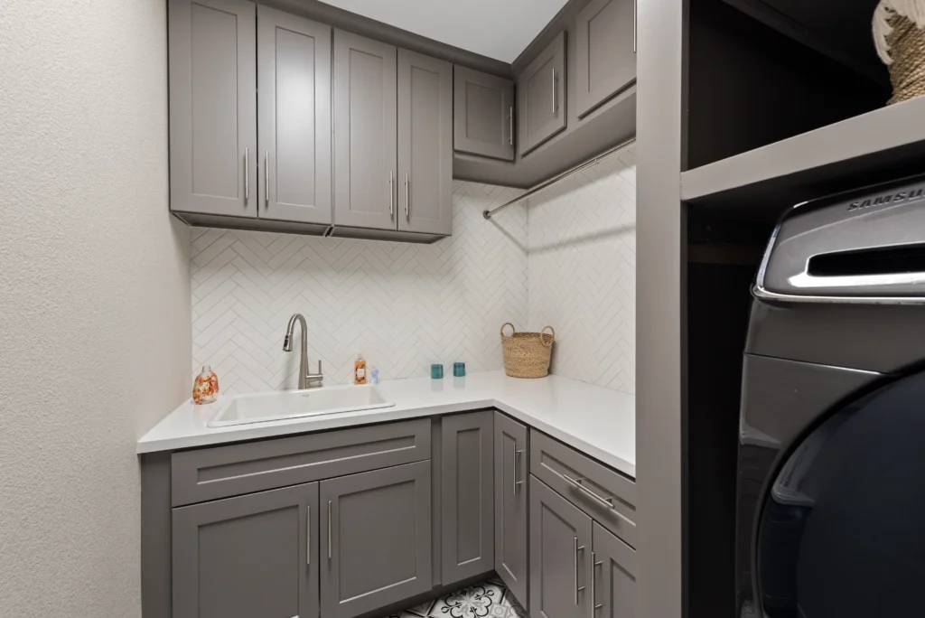 Sleek modern laundry room design with gray cabinetry, white countertop, and integrated utility sink.