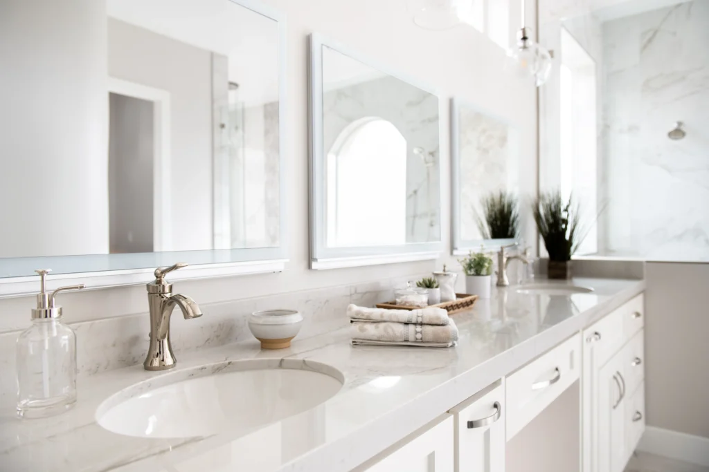 Modern bathroom with elegant marble sinks, gold faucets, large mirrors, and soothing decor.