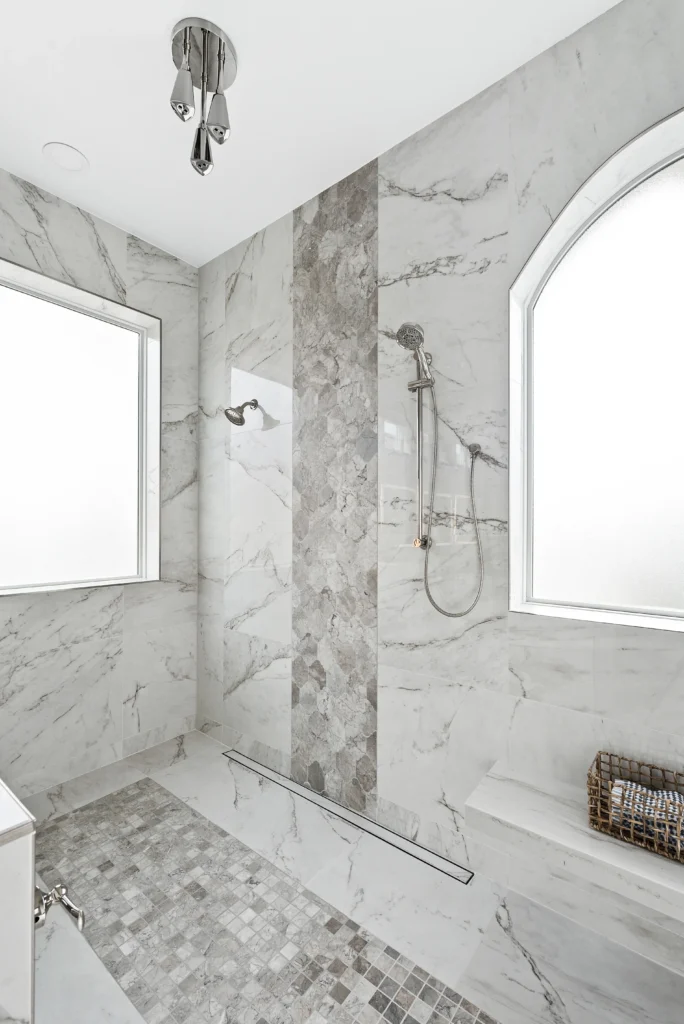 Elegant modern shower with gray marble tiles, frosted windows, and polished metal fixtures.