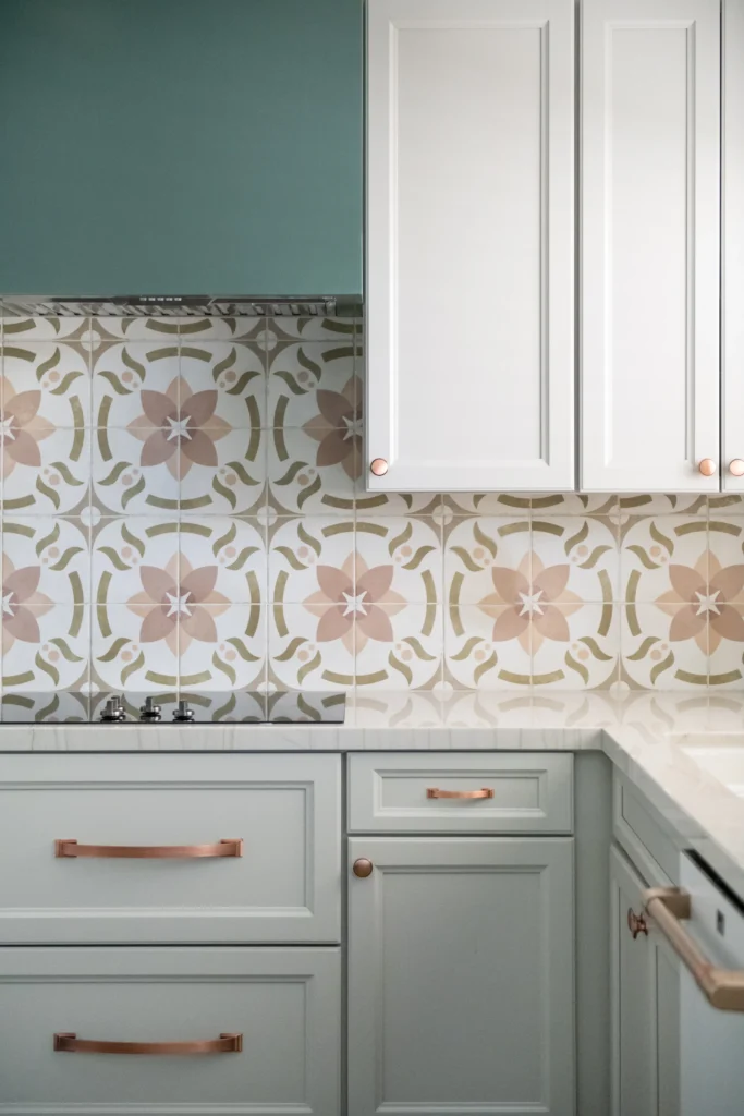 Modern kitchen design featuring green cabinetry, floral backsplash, and elegant copper accents.