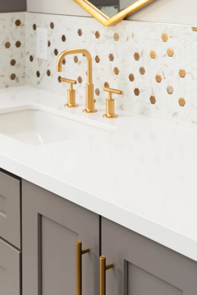 Sophisticated Underwood bathroom with gold faucet, marble backsplash, and elegant white countertop.