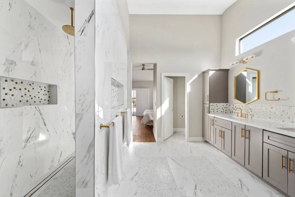 Luxurious modern master bath with marble walk-in shower, gold fixtures, and elegant double vanity.