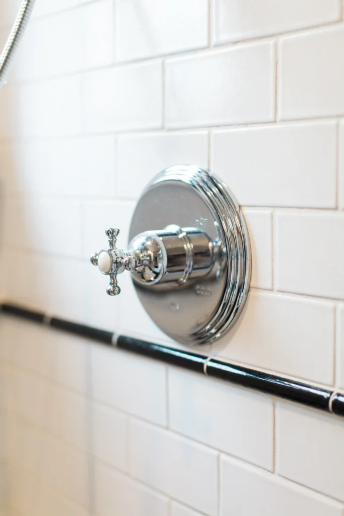 Elegant chrome shower valve on white tiles, combining vintage charm with modern design elements.