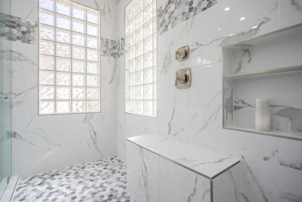 Modern spa bathroom with elegant marble tiles and bright glass block windows for a serene escape.