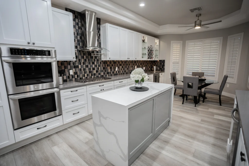 Sleek modern kitchen with white cabinetry, gray backsplash, and a spacious white-veined island.