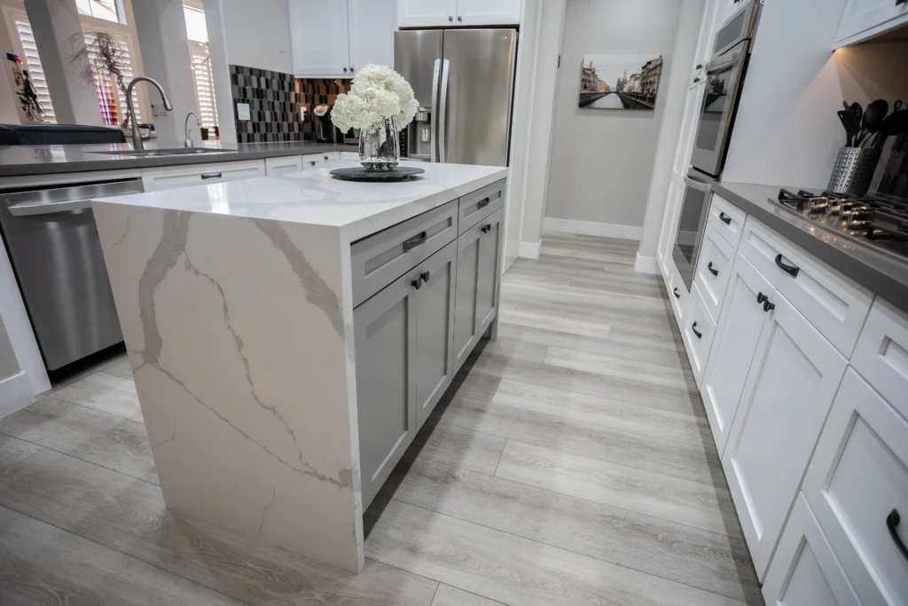 Modern kitchen with elegant waterfall island, gray cabinetry, and bright, airy design elements.