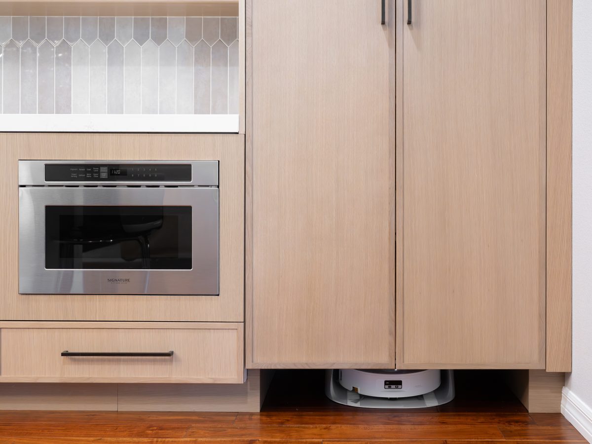 Kitchen with warm stained oak slim shaker cabinetry and dark bronze hardware featuring custom appliance tower, Reveal Interior Design Las Vegas