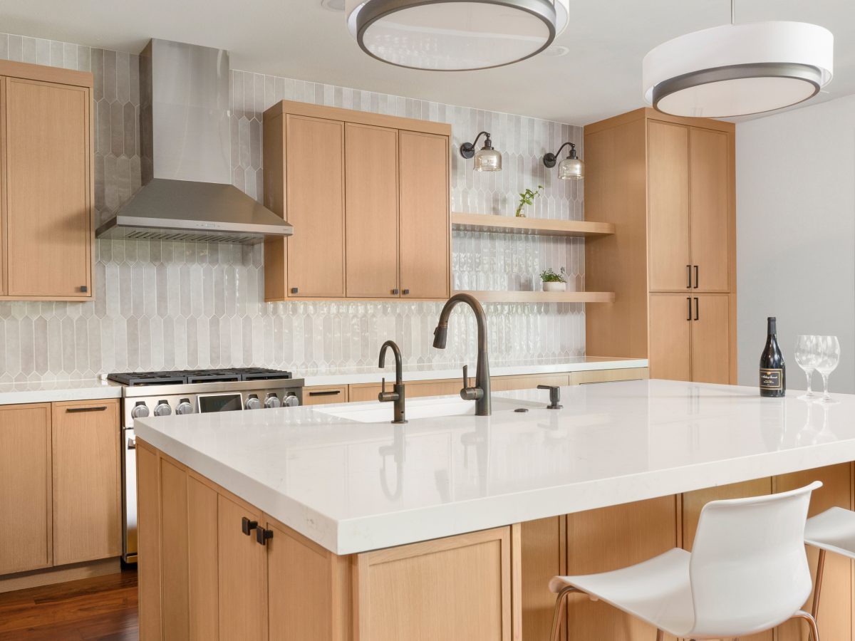 Warm oak kitchen with quartz island, handmade-style picket tile backsplash, and dark bronze fixtures, Reveal Interior Design Las Vegas