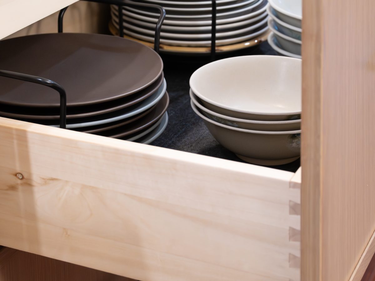 Kitchen pull-out drawer with organized dishware storage in warm oak cabinetry, Reveal Interior Design Las Vegas