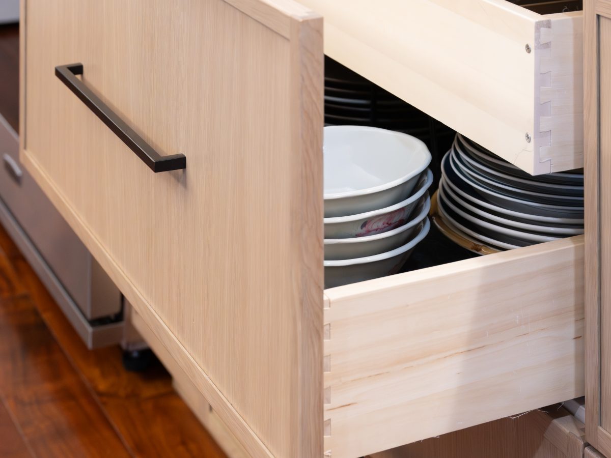 Kitchen island pull-out drawer storage with warm stained oak cabinetry and dark bronze hardware, Reveal Interior Design Las Vegas
