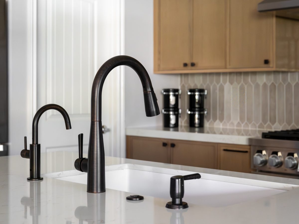 Kitchen island sink with dark bronze faucet fixtures and warm off-white quartz countertops, Reveal Interior Design Las Vegas