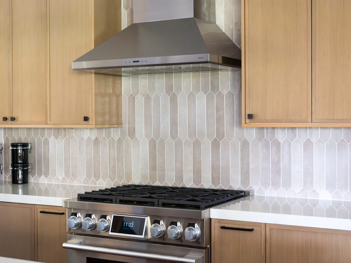 Kitchen with warm stained oak slim shaker cabinetry, picket backsplash tile, and quartz countertops, Reveal Interior Design Las Vegas